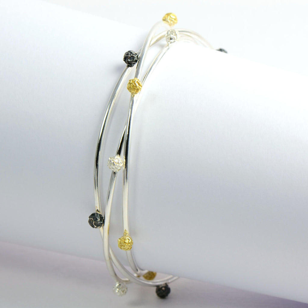 A Set of three bangles, with stellar peppercorns design accented with gold vermiel, dark and bright silver sterling