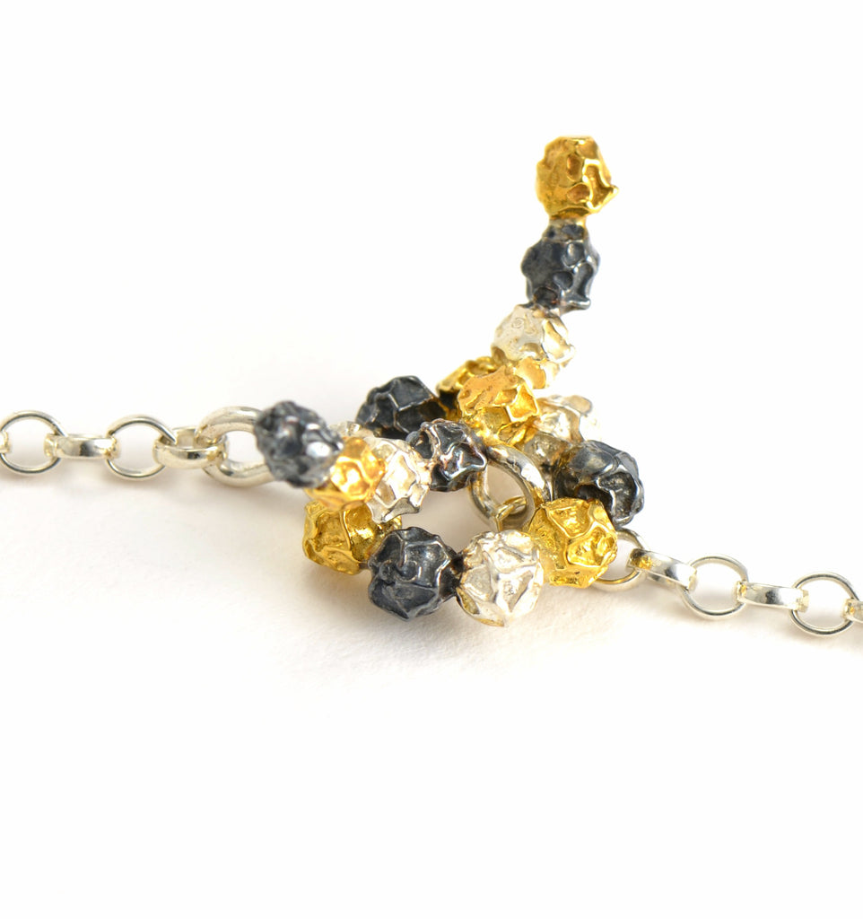 A silver and golden three peppercorn stick necklace