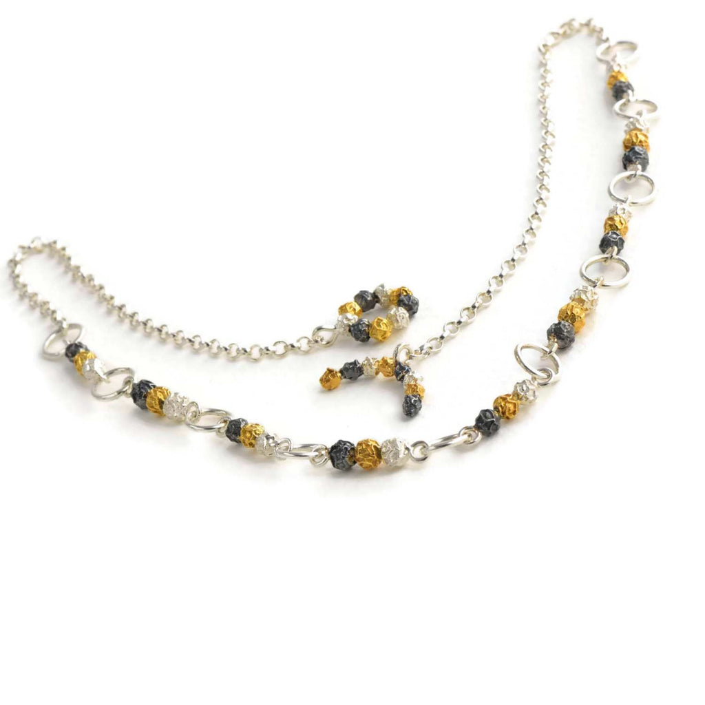 A silver and golden three peppercorn stick necklace